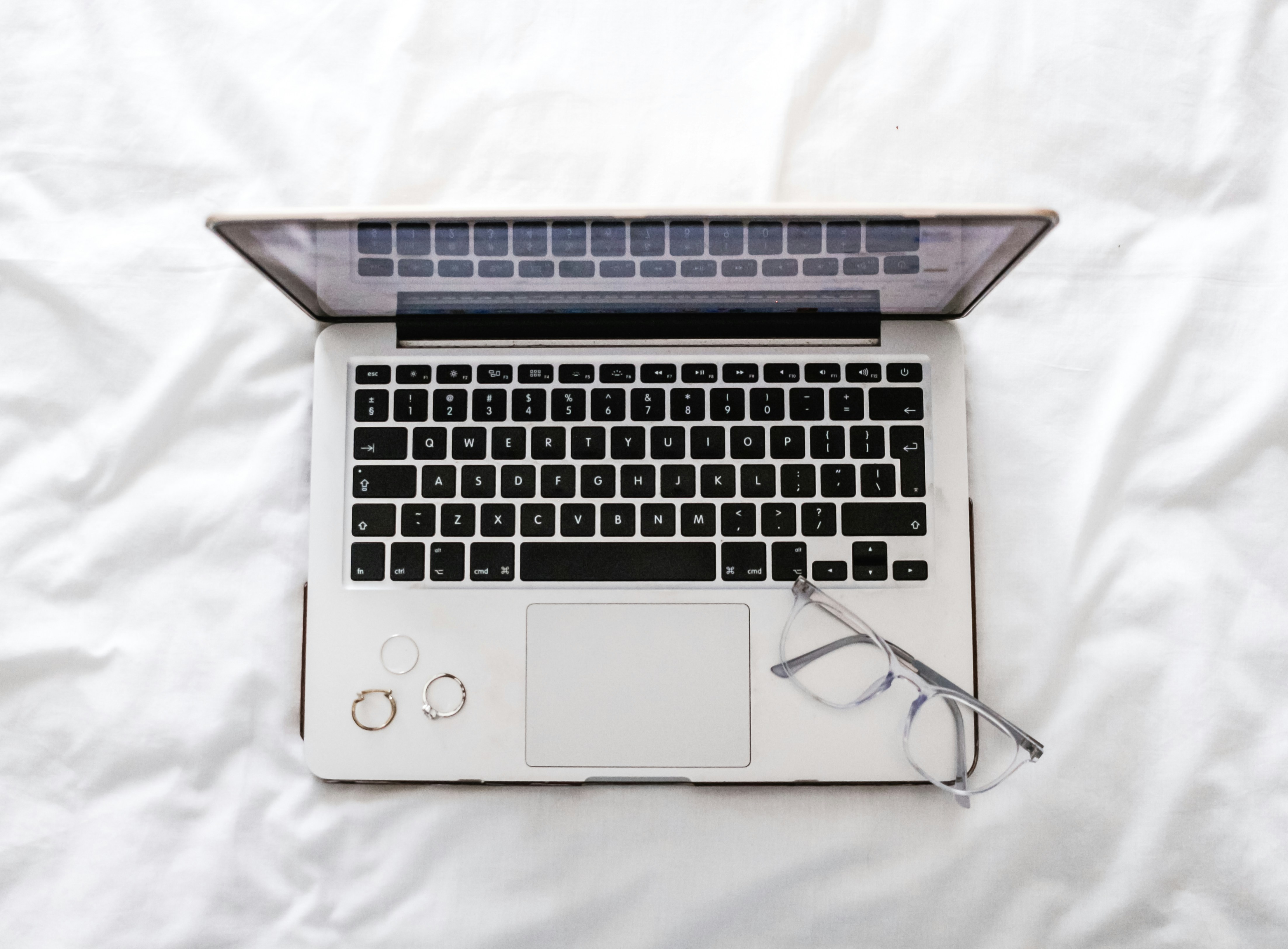 Laptop and Glasses on White Bed